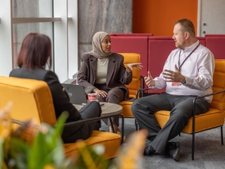 Two women and man on orange seats meeting