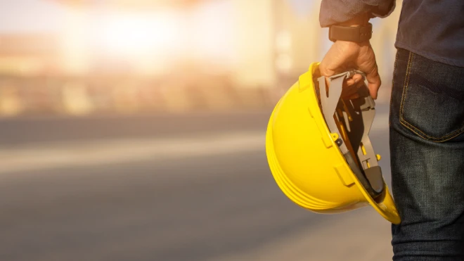 Construction worker holding safety helmet